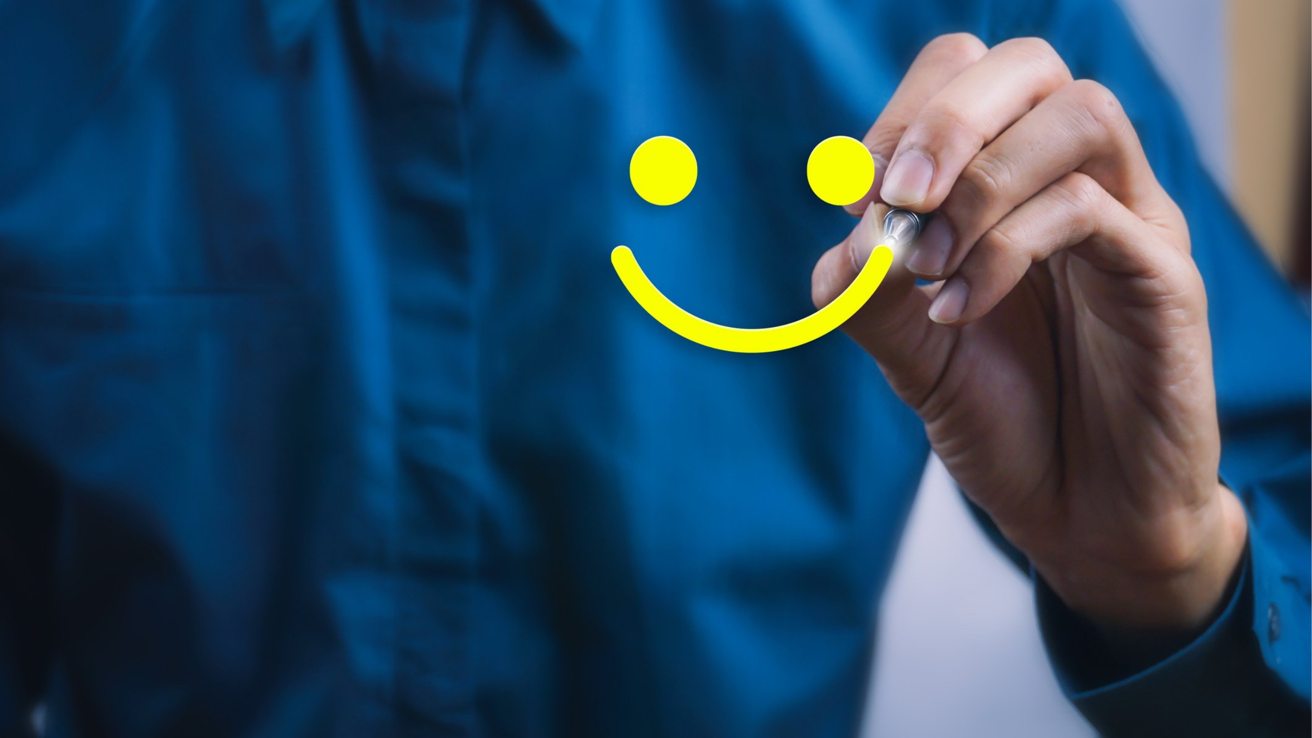 Person in blue shirt drawing a smiley face in yellow
