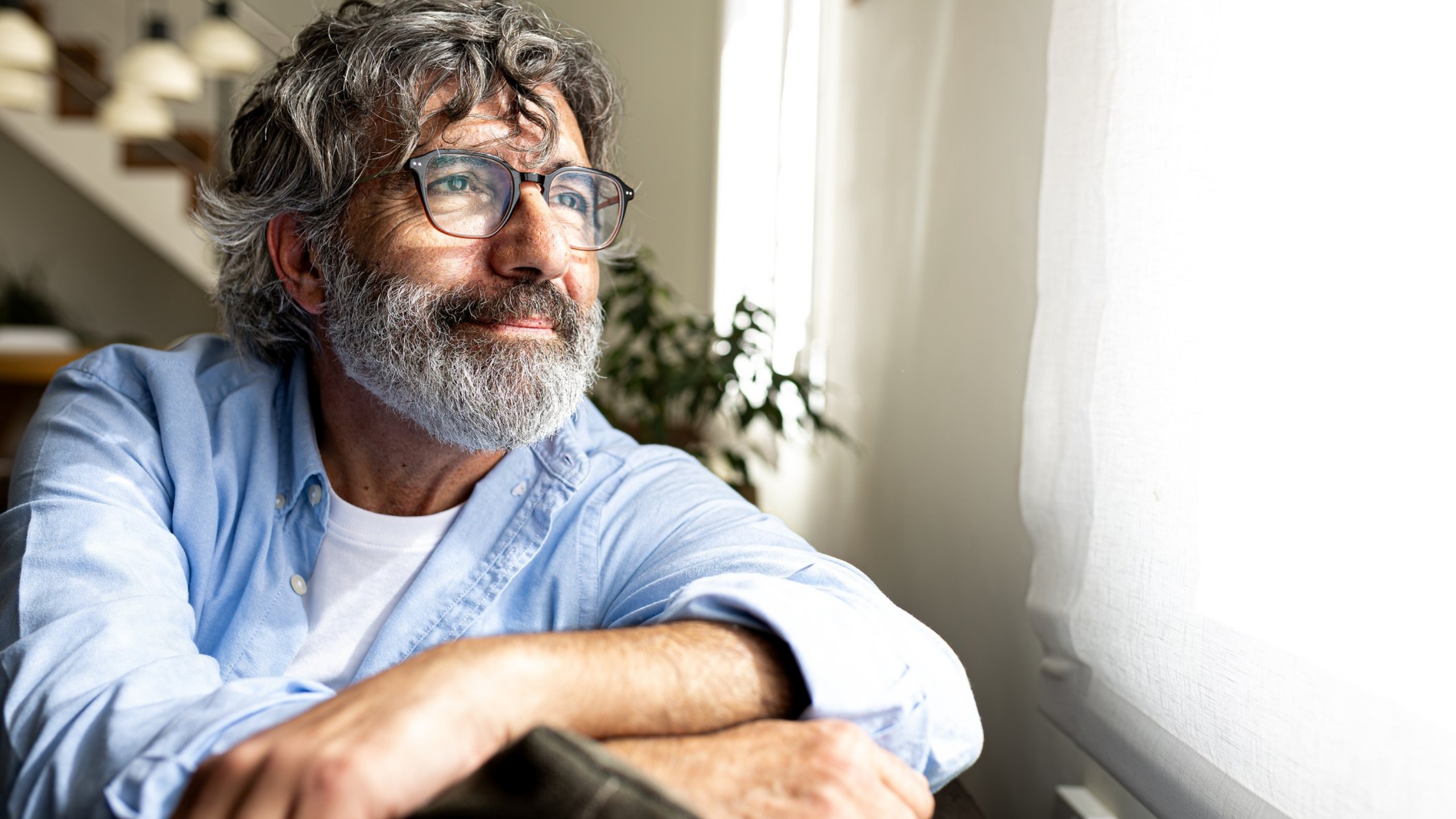 Man with grey hair and beard with glasses looking to the future